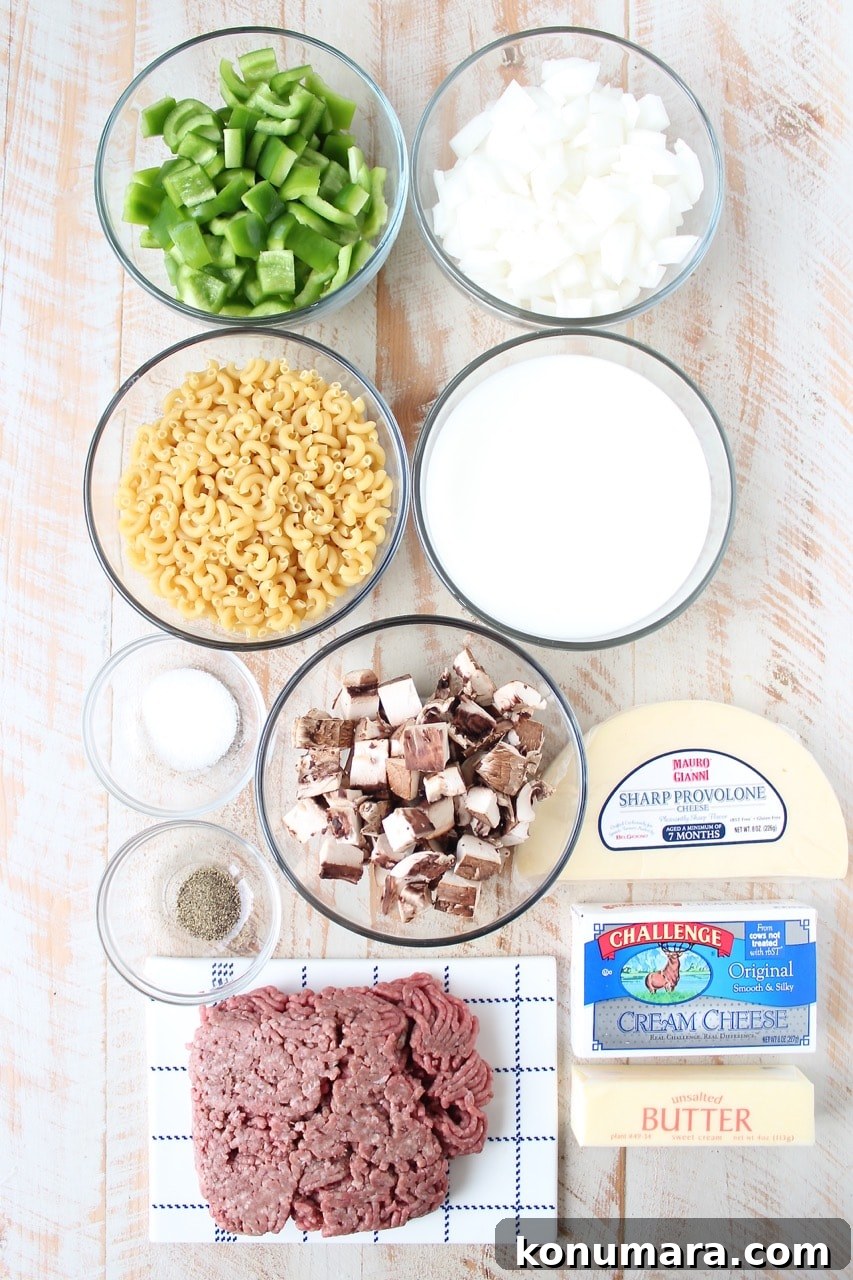 Loaded Philly Cheesesteak Mac and Cheese 3 ingredients for Philly cheesesteak mac and cheese on white wood board