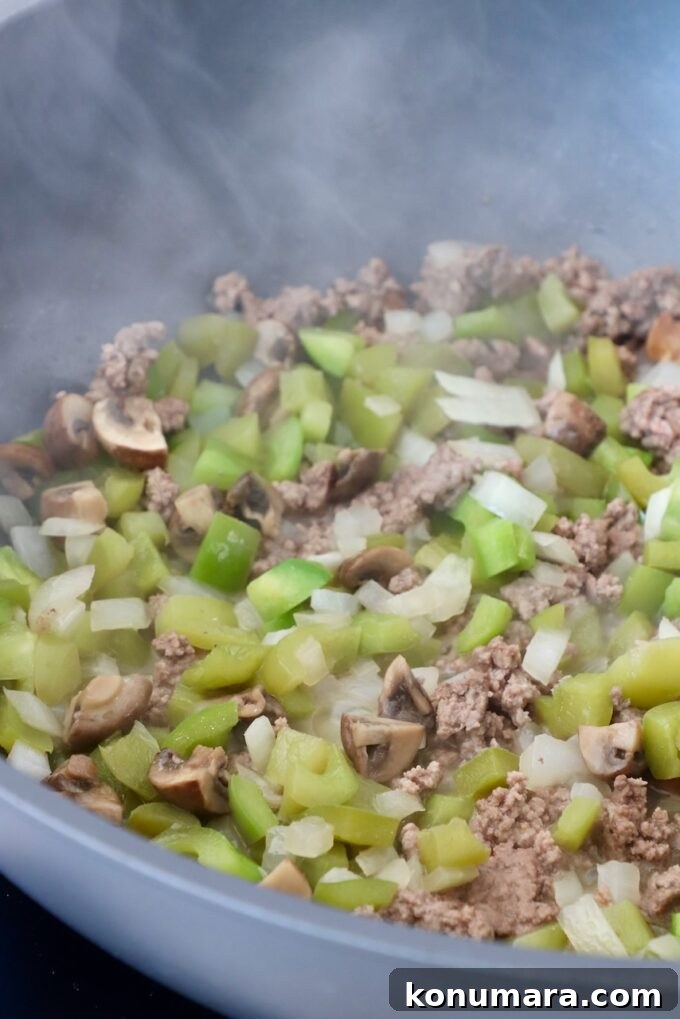 Loaded Philly Cheesesteak Mac and Cheese 4 cooked bell peppers, onions and ground beef in skillet