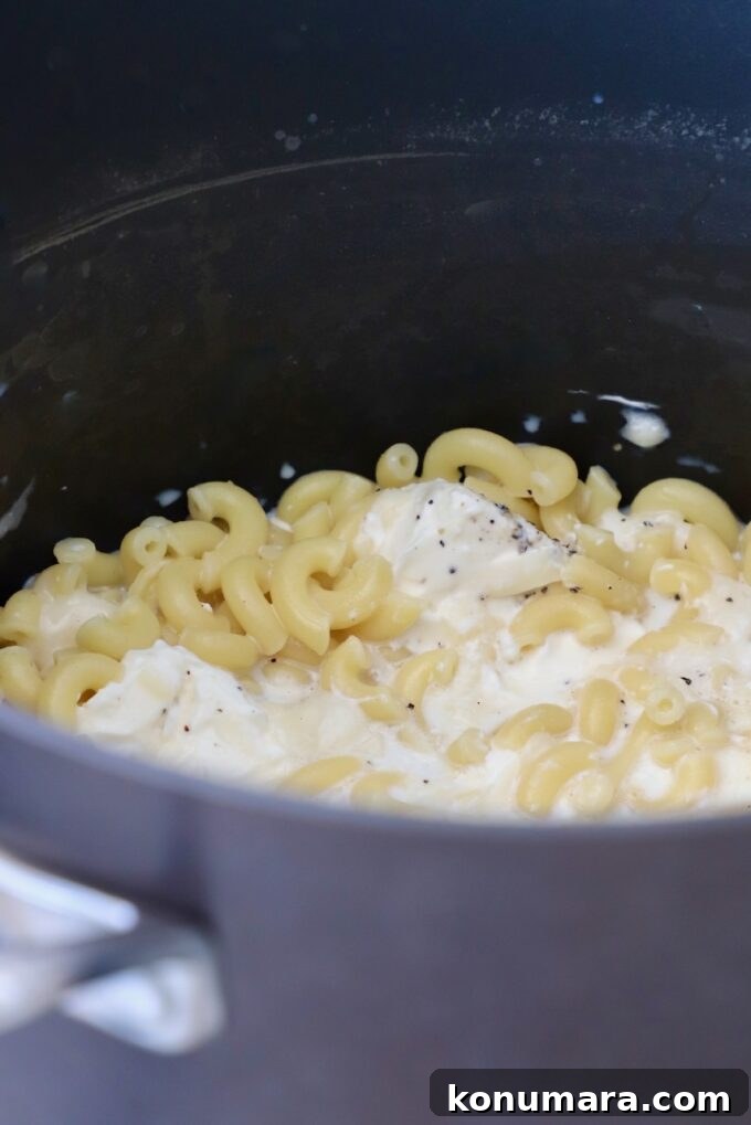 Loaded Philly Cheesesteak Mac and Cheese 5 cooked macaroni noodles in pot with milk and cheese