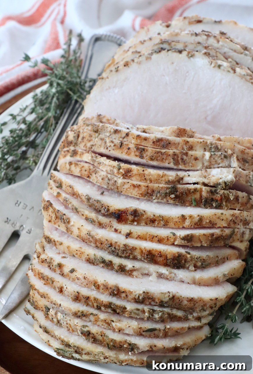 Juicy Sous-Vide Turkey Breast Recipe 2 sliced turkey breast on a plate with a serving fork and fresh thyme sprigs
