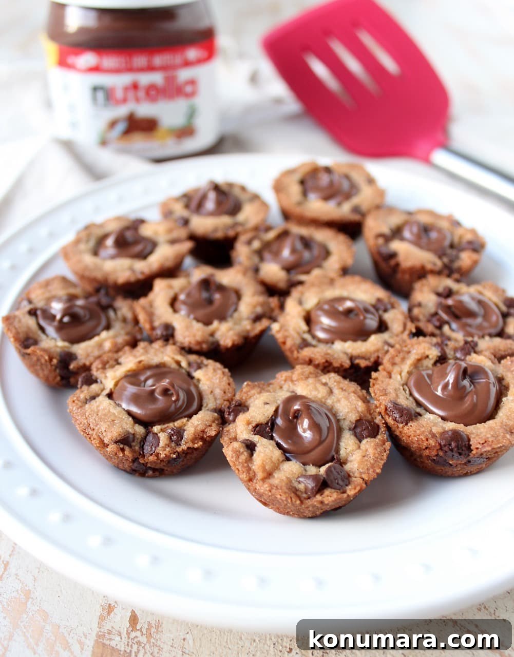 Nutella-Stuffed Chocolate Chip Cookie Cups Recipe 2 chocolate chip cookie cups on plate filled with nutella