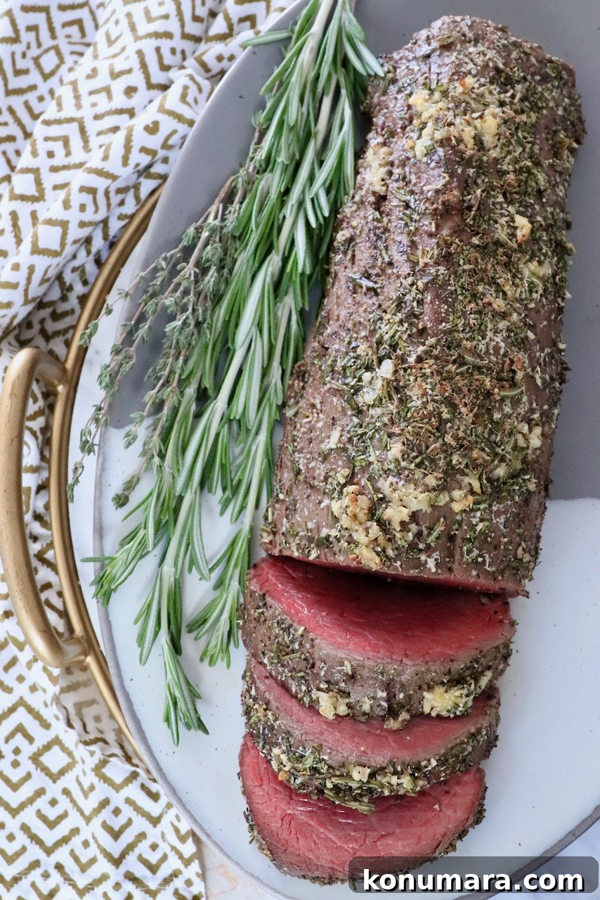 herb rubbed beef tenderloin on a plate with fresh herbs