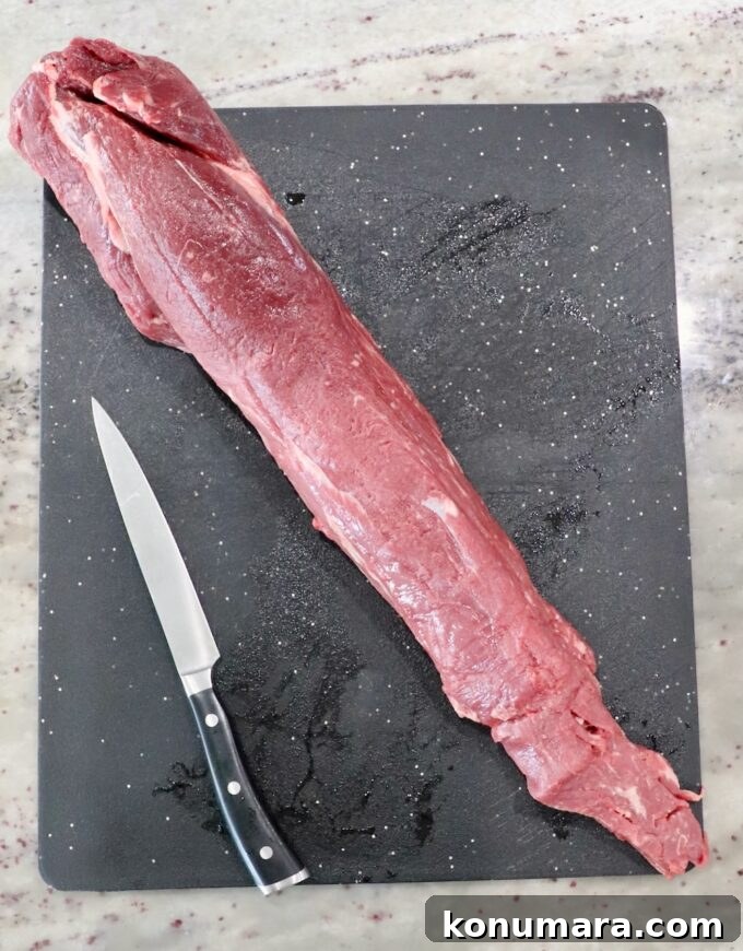 whole beef tenderloin on a cutting board with a knife