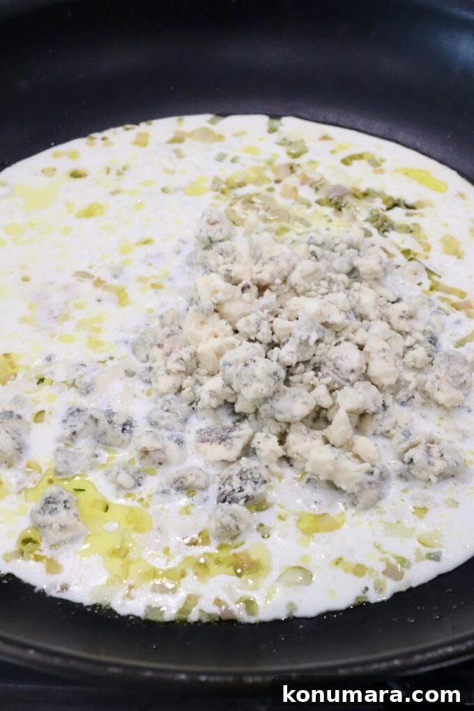 gorgonzola crumbles on top of a cream sauce in a skillet