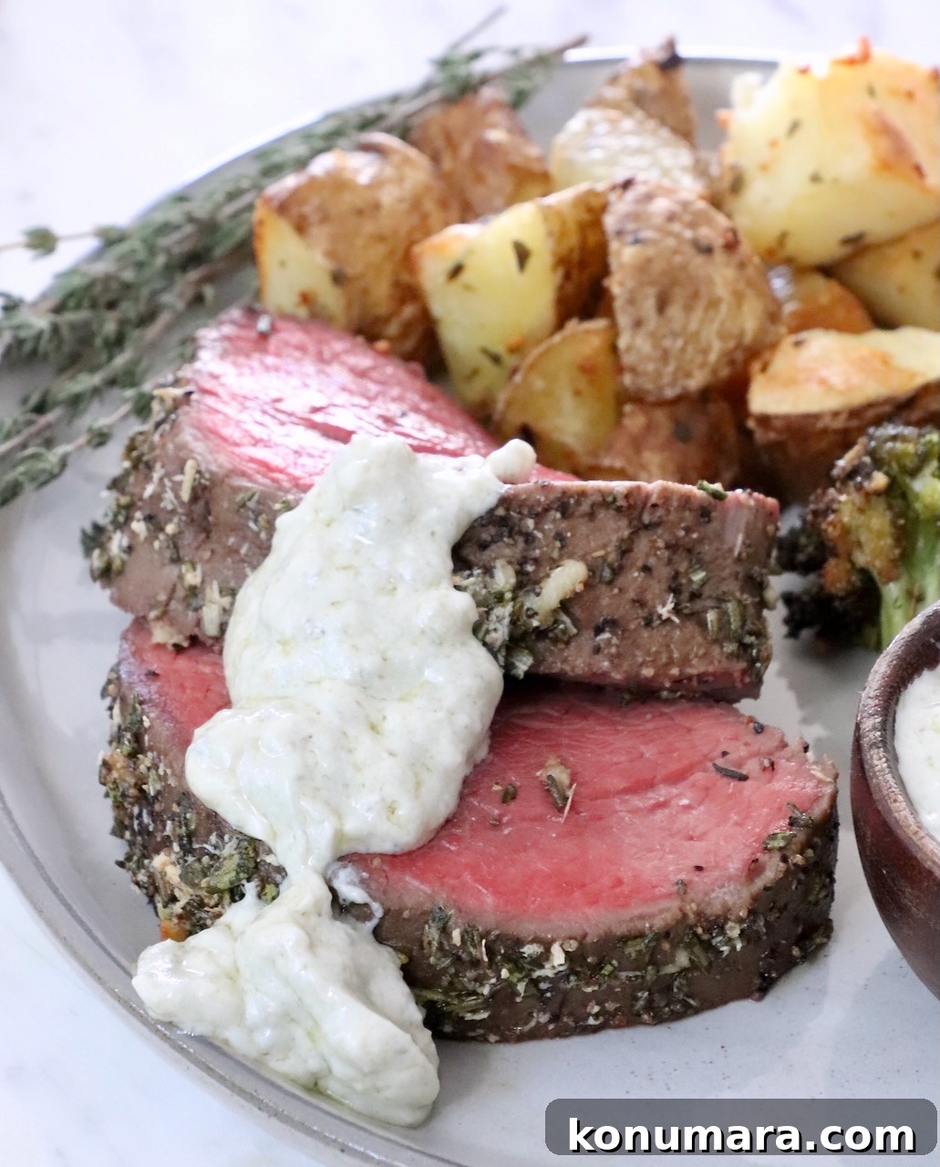 gorgonzola cream sauce on top of slices of beef tenderloin on a plate with roasted potatoes