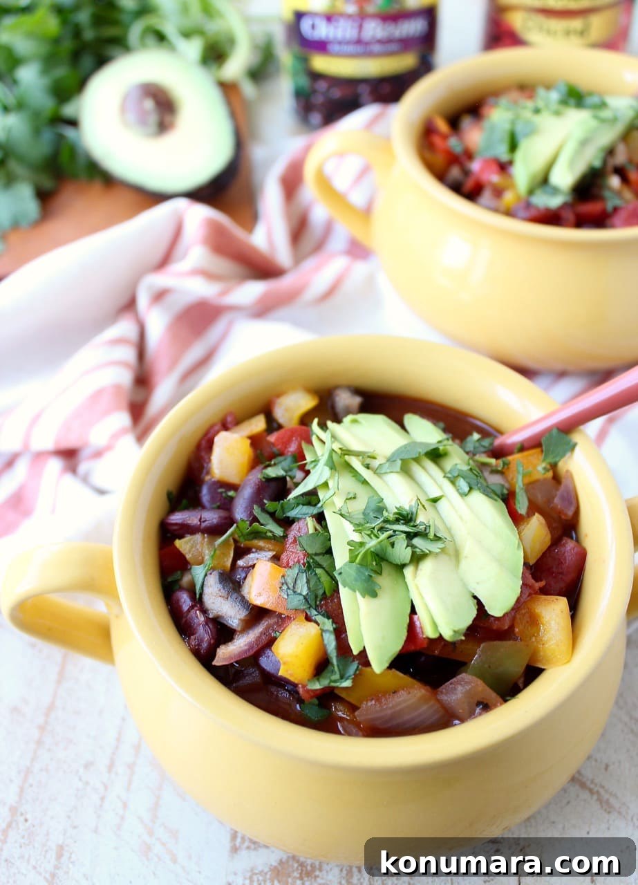 chili in yellow crocks topped with sliced avocado and chopped cilantro