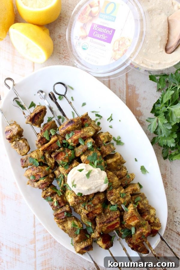Grilled Mediterranean Chicken Skewers with Lemon and Herbs 3 Skewers on the grill with charred edges and green spinach marinade