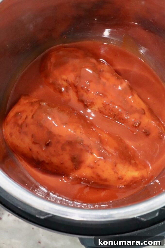 seasoned chicken breasts covered in buffalo sauce in an Instant Pot