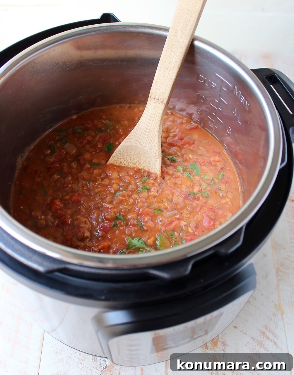 Instant Pot Chicken Tikka Masala with Lentils Recipe 3 lentils and chicken in sauce in an Instant Pot with a wooden spoon
