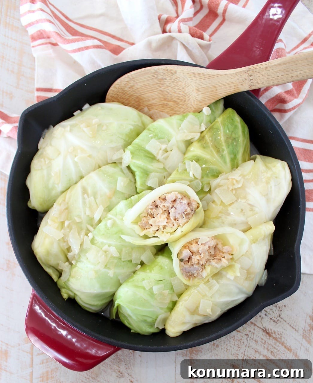 cabbage rolls in a skillet with a wooden spoon
