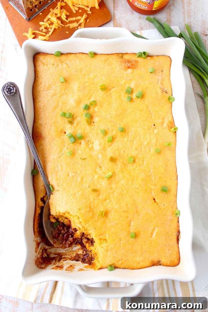 cornbread chili pie in casserole dish with serving spoon