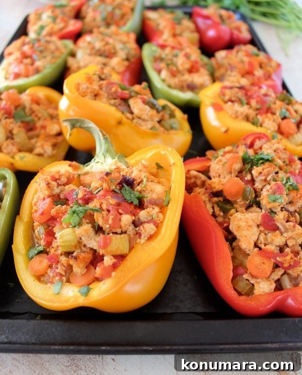 Cooked ground chicken, carrots and celery stuffed in bell pepper halves on baking sheet