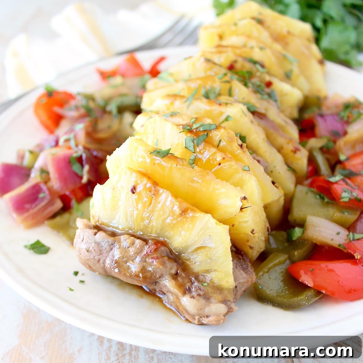 Glazed Pineapple Teriyaki Pork Tenderloin Recipe 2 cooked pork tenderloin stuffed with slices of pineapple on a plate with diced bell peppers and onions