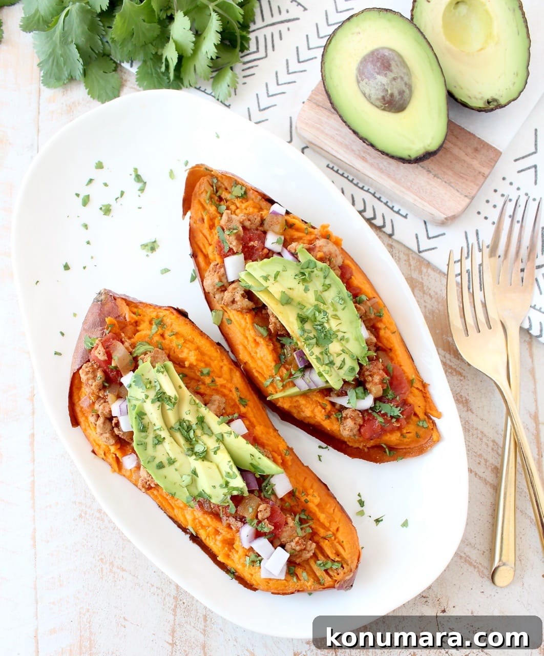 Smoky Chipotle Chili Stuffed Sweet Potatoes Recipe 2 baked sweet potato cut in half and topped with chili and sliced avocado on a white plate
