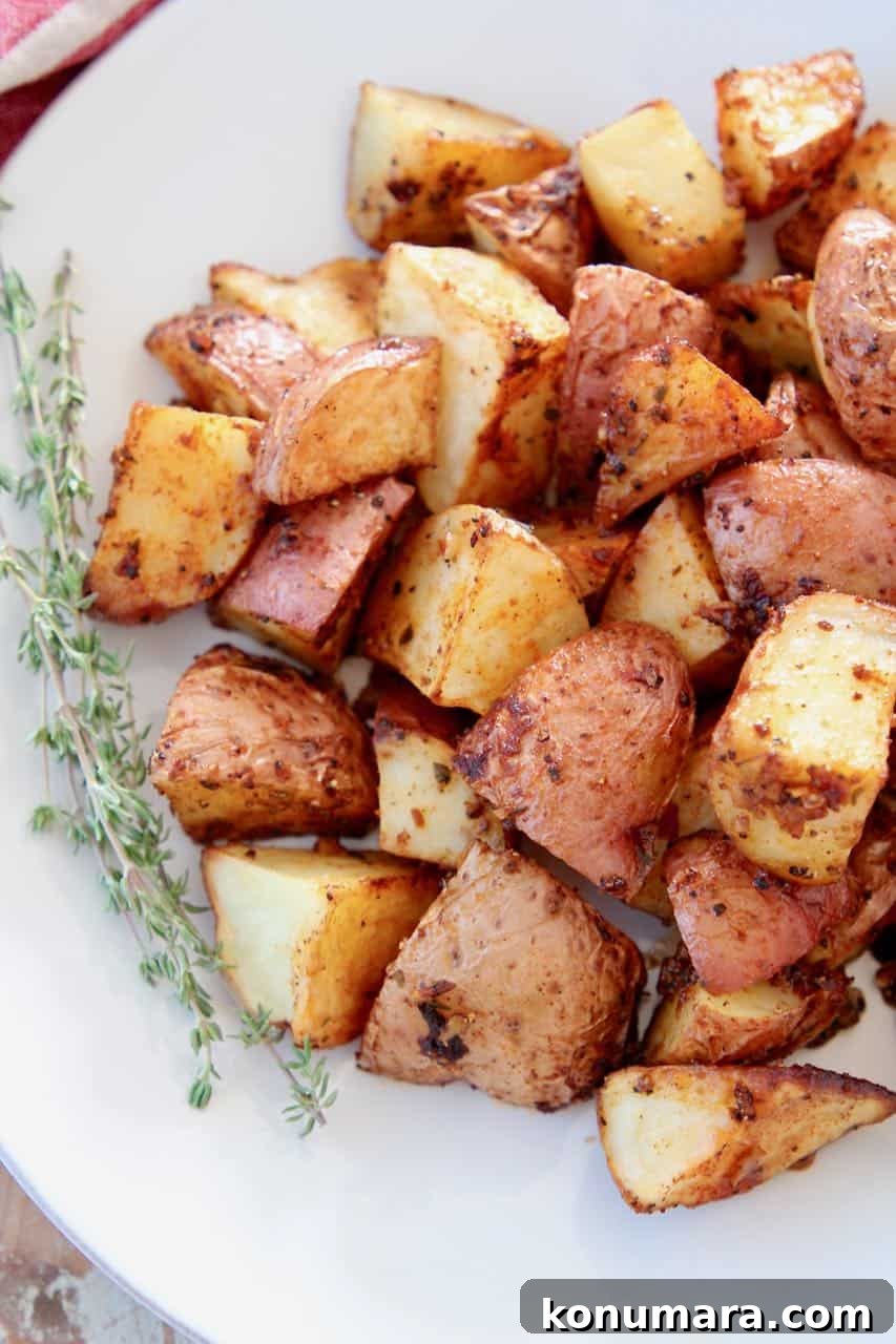 Crispy Cajun Roasted Potatoes Recipe 3 Overhead image of roasted cubed red potatoes on plate with thyme sprigs