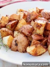 Crispy baked Cajun red potatoes on white plate with fresh thyme sprigs