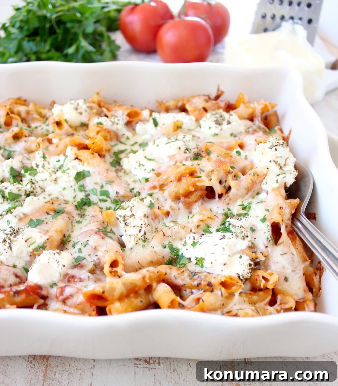 baked ziti in casserole dish topped with ricotta cheese and herbs