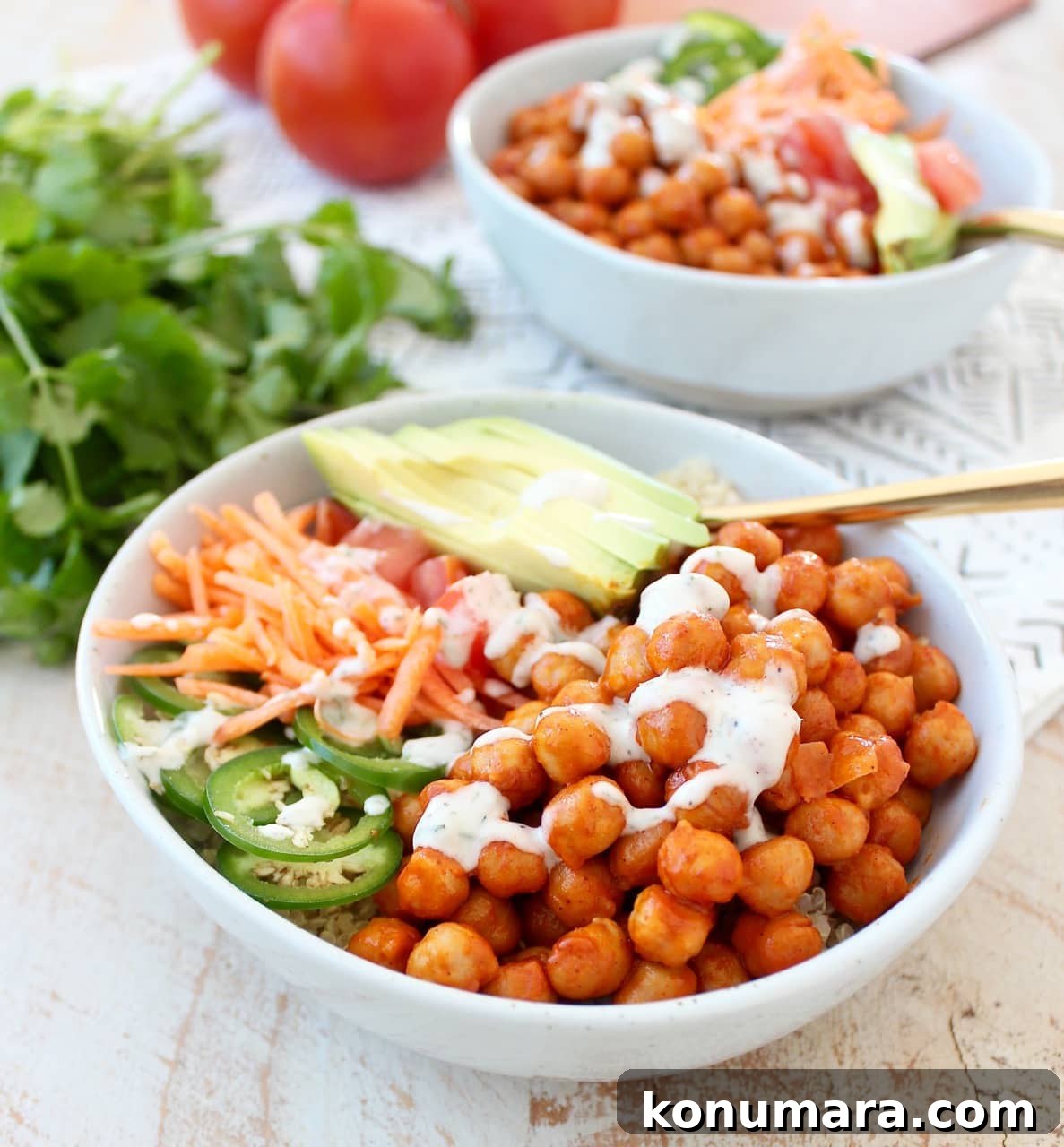 Spicy Vegan Buffalo Chickpea Buddha Bowl Recipe 3 bowls filled with chickpeas tossed in buffalo sauce and sliced vegetables and a gold fork in the bowl