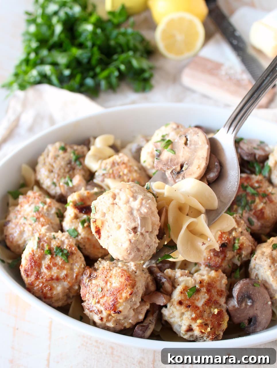 serving fork dipping cooked meatballs, noodles and mushrooms out of a casserole dish