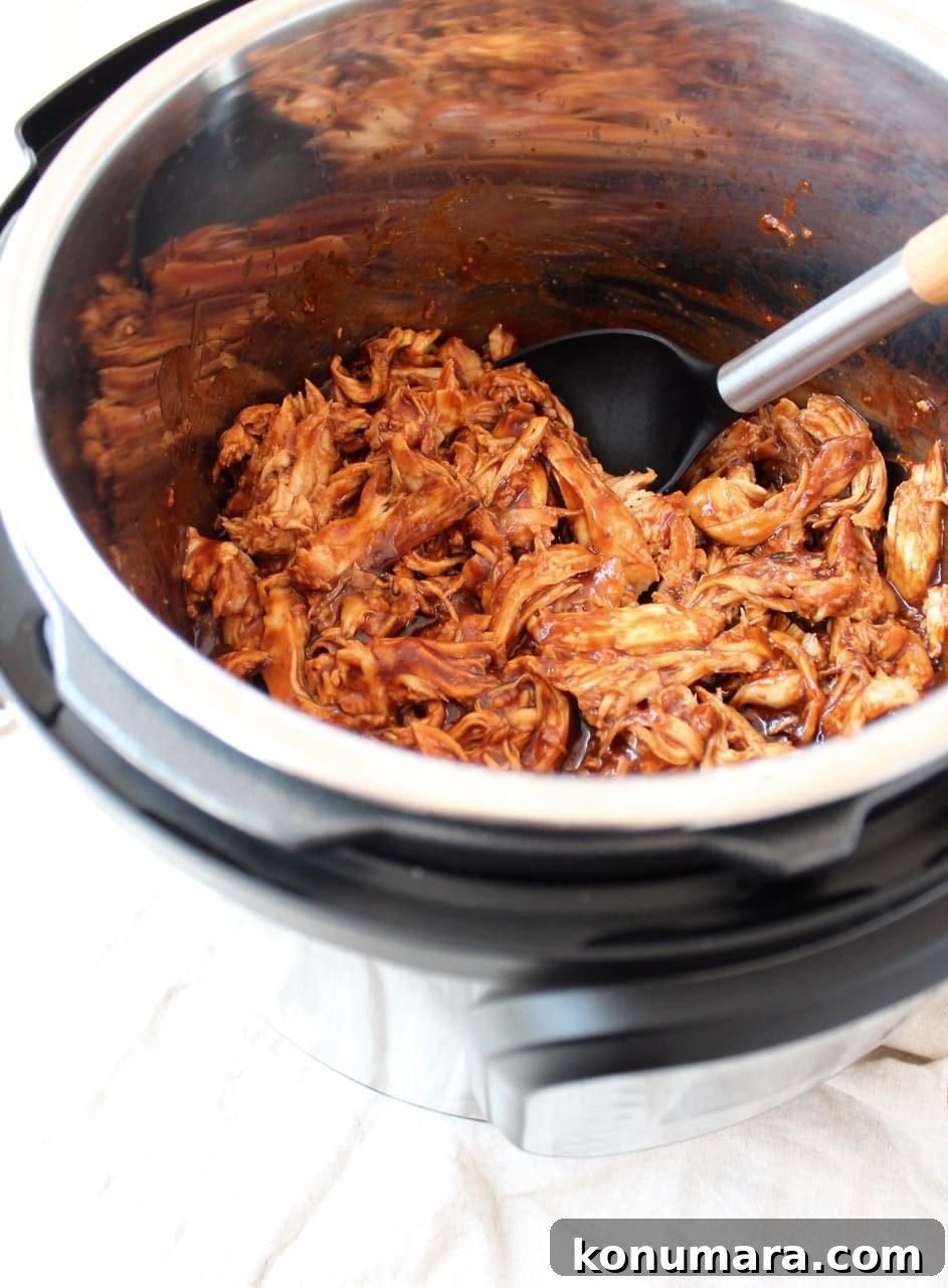 Smoky Instant Pot BBQ Chicken Recipe 3 Shredded BBQ chicken in an Instant Pot with a spoon.