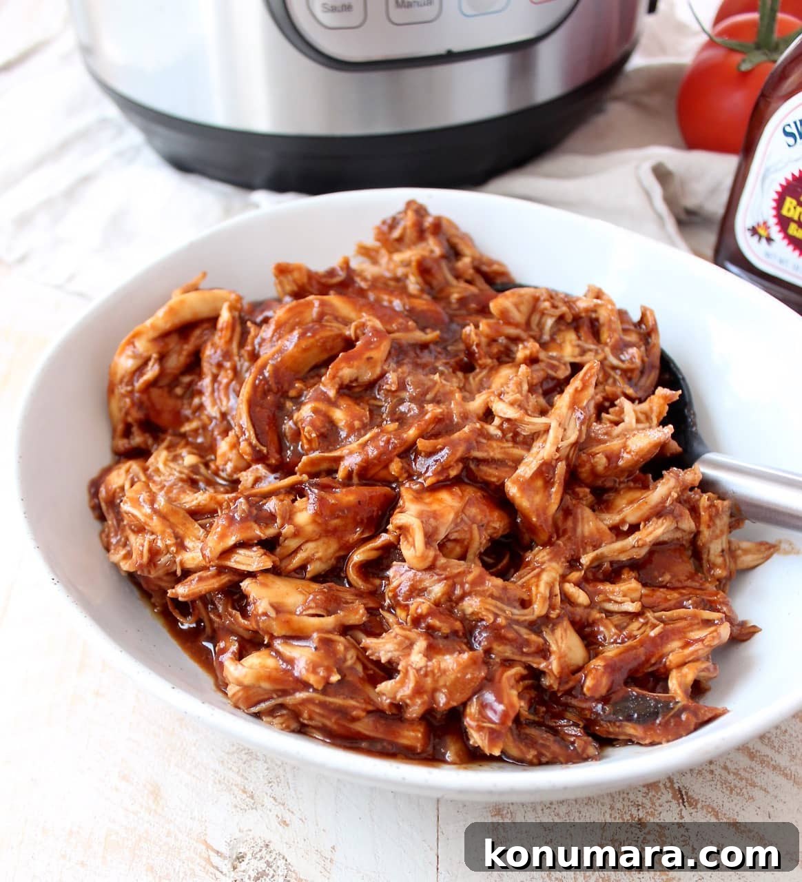 Smoky Instant Pot BBQ Chicken Recipe 4 Shredded BBQ chicken in a white bowl with a spoon.