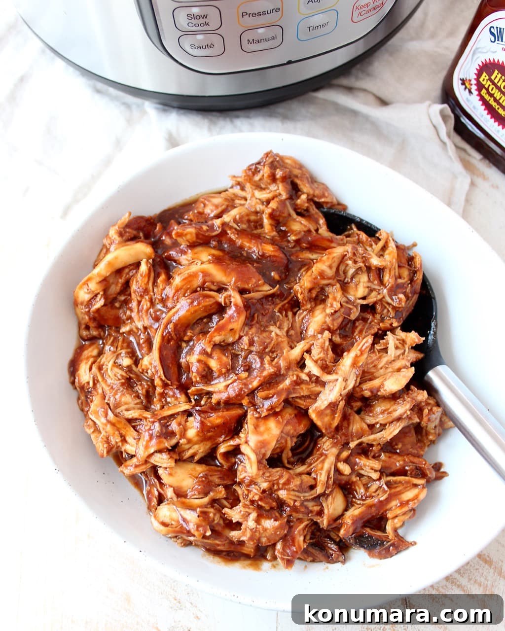 Smoky Instant Pot BBQ Chicken Recipe 5 Shredded BBQ chicken in a white bowl with a spoon.
