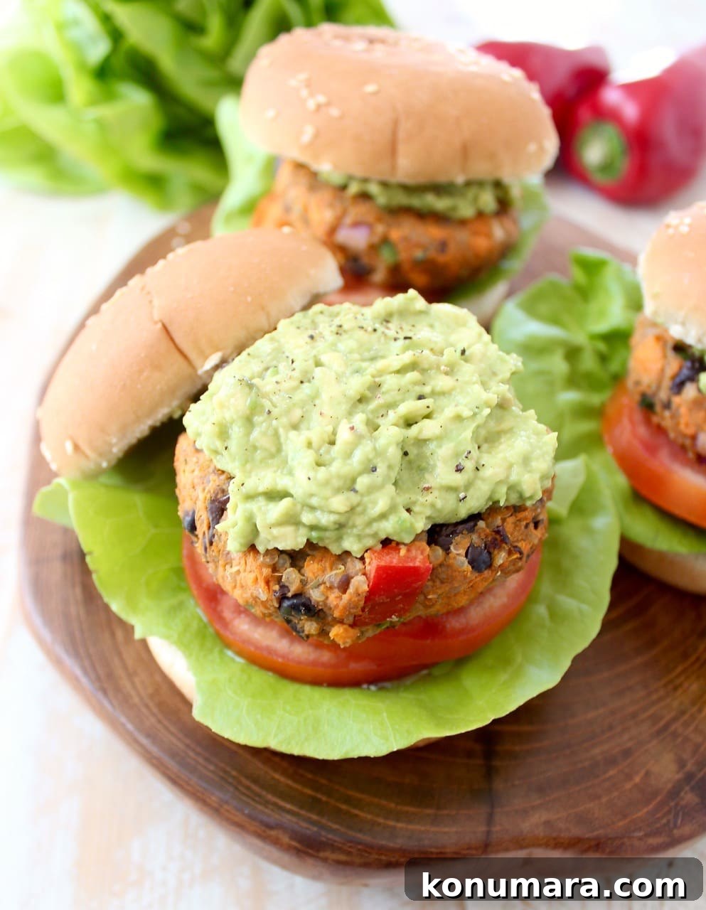 Veggie Burgers topped with mashed Avocado on a wood board