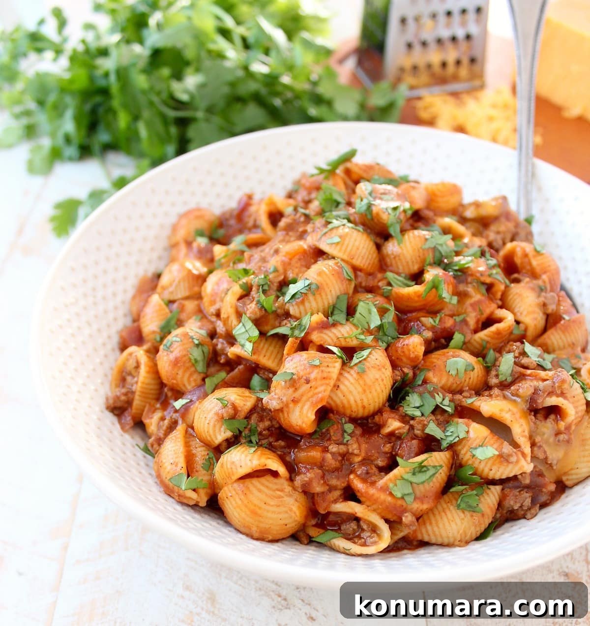 pasta shells with meat sauce in large bowl with serving spoon