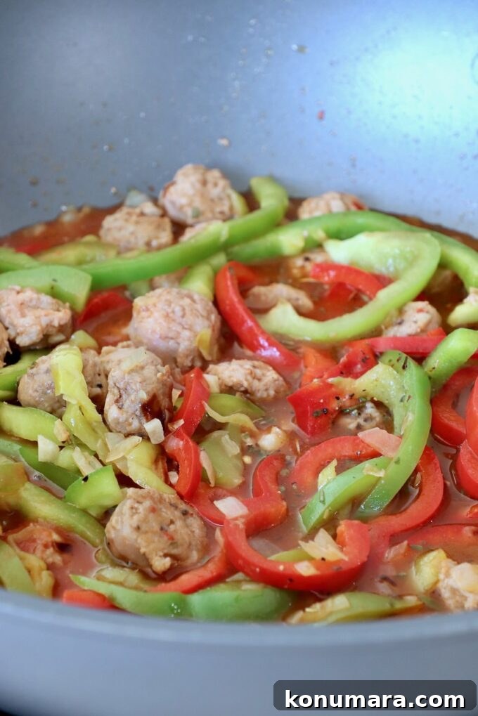 sliced bell peppers and Italian sausage in broth in large pan