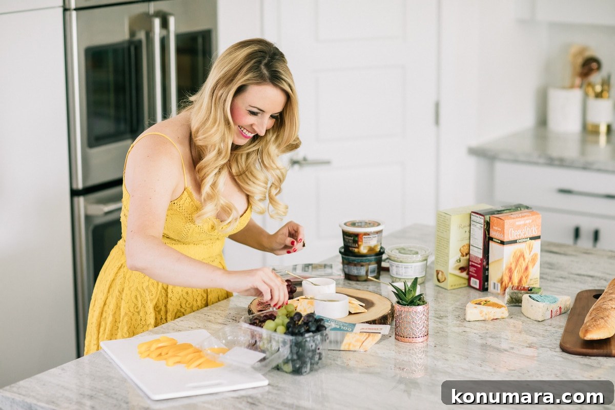 Whitney Bond making a cheese plate with grapes, olives and crackers in kitchen