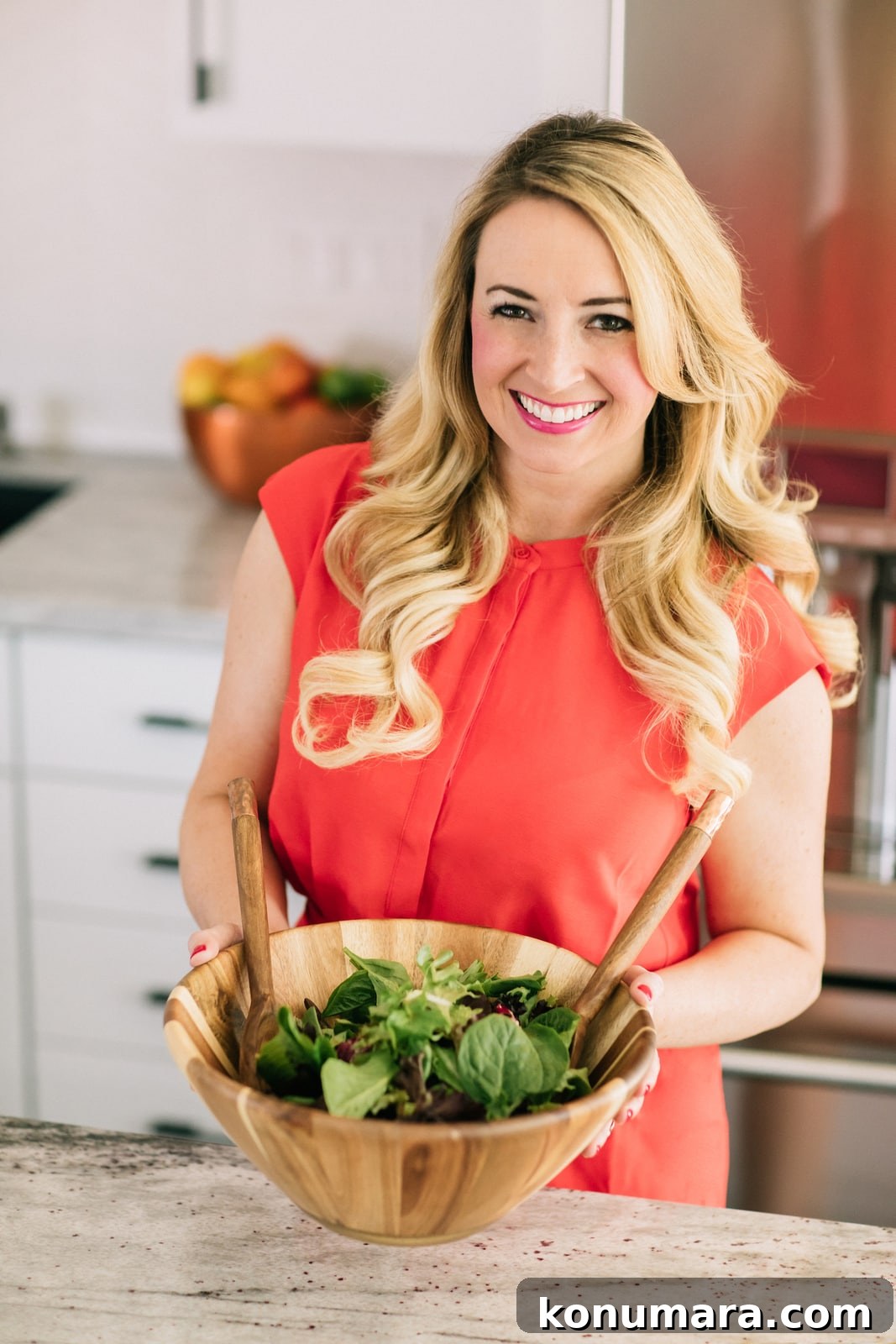 whitney bond in orange dress holding salad bowl in kitchen
