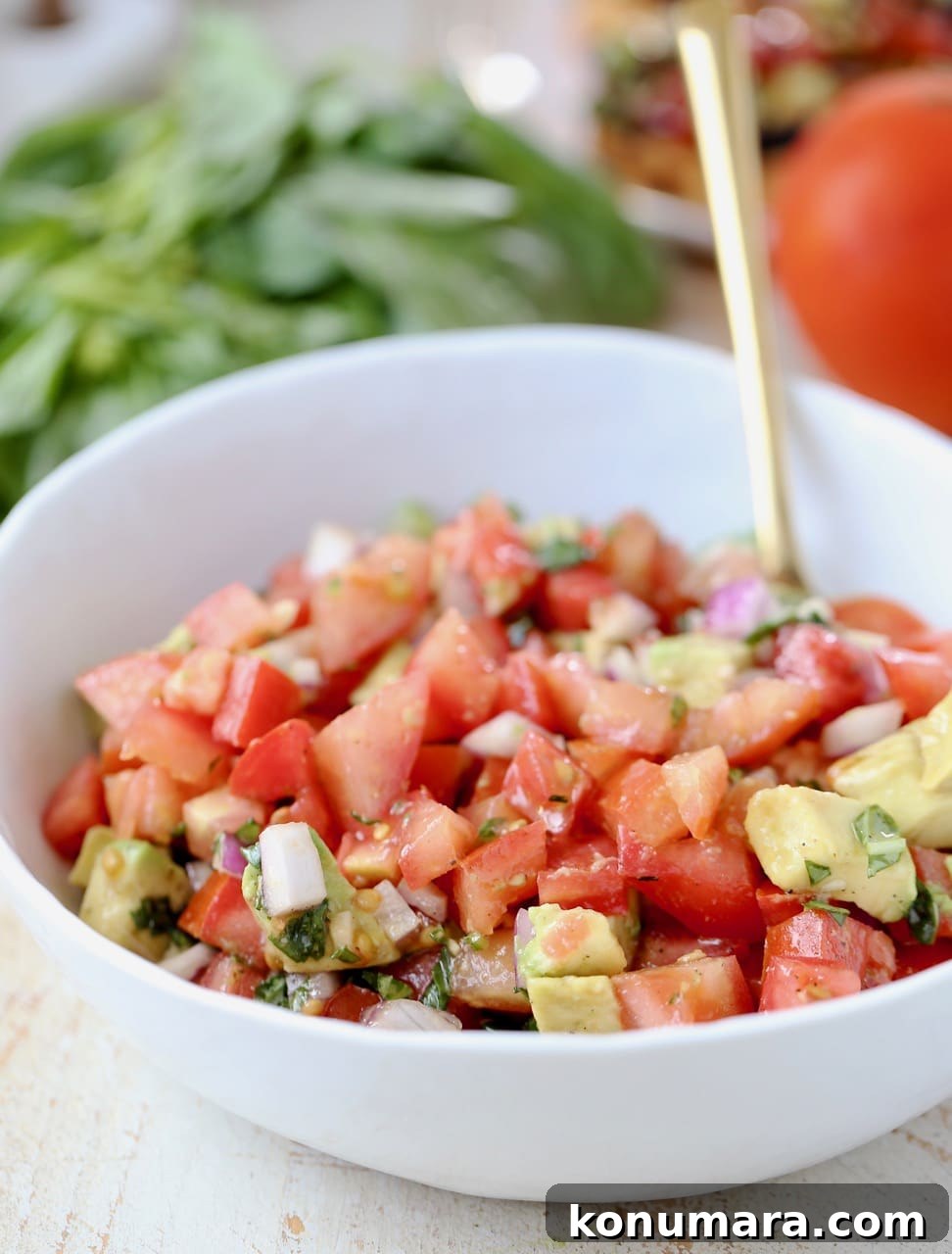 diced tomatoes, onions and avocado mixed together in a white bowl