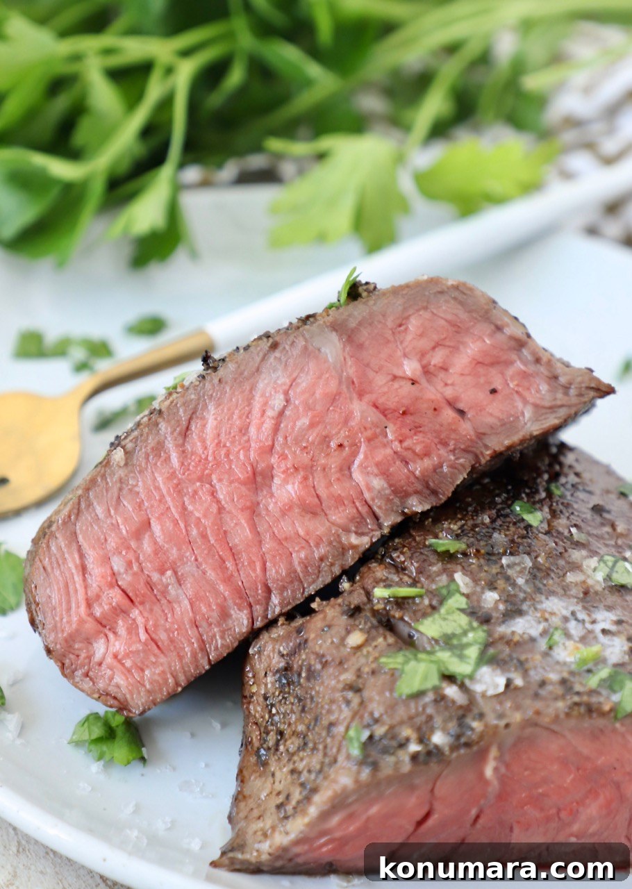 sous vide steak sliced in half on plate with fork and fresh parsley