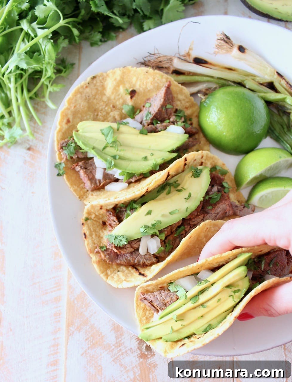 Hand Holding Carne Asada Tacos with Avocado