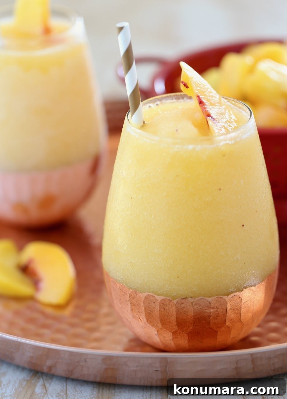 Frozen Peach Sangria Recipe - Refreshing Summer Cocktail 3 Frozen Peach Sangria in Glass with Copper Bottom and Gold Straws on Copper Tray with Fresh Peaches