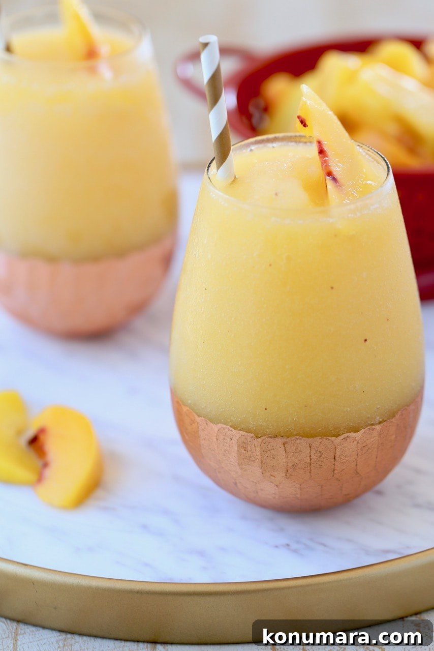 Frozen Peach Sangria Recipe - Refreshing Summer Cocktail 4 Frozen Peach Sangria in Copper Bottom Glasses on White Marble Serving Tray with Fresh Peaches