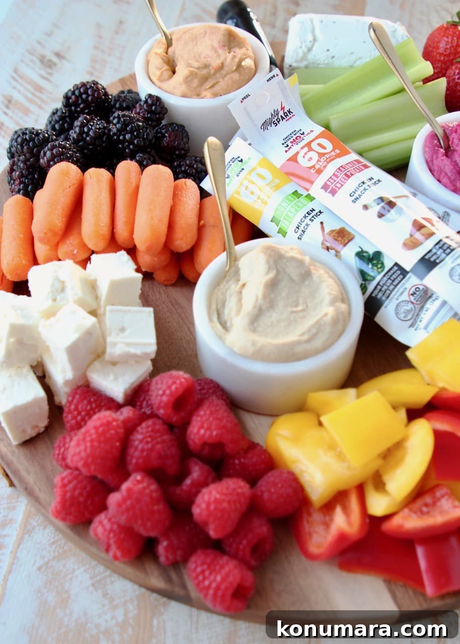 Low-Calorie Charcuterie Board Recipes That Impress 4 Low Calorie Charcuterie Board with Hummus, Veggies, Berries, Feta Cheese, Goat Cheese and Chicken Snack Sticks