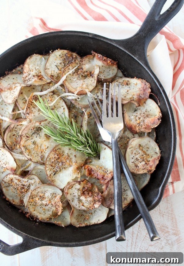A cast iron skillet on a wooden surface filled with sliced and seasoned potatoes and two forks.