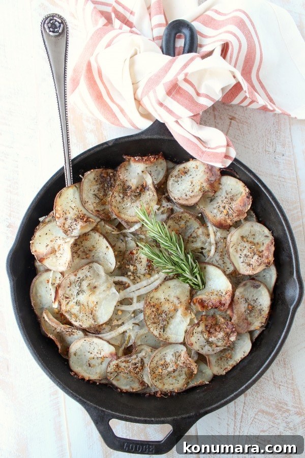 A cast iron skillet on a wooden surface filled with sliced and seasoned potatoes with a fork.