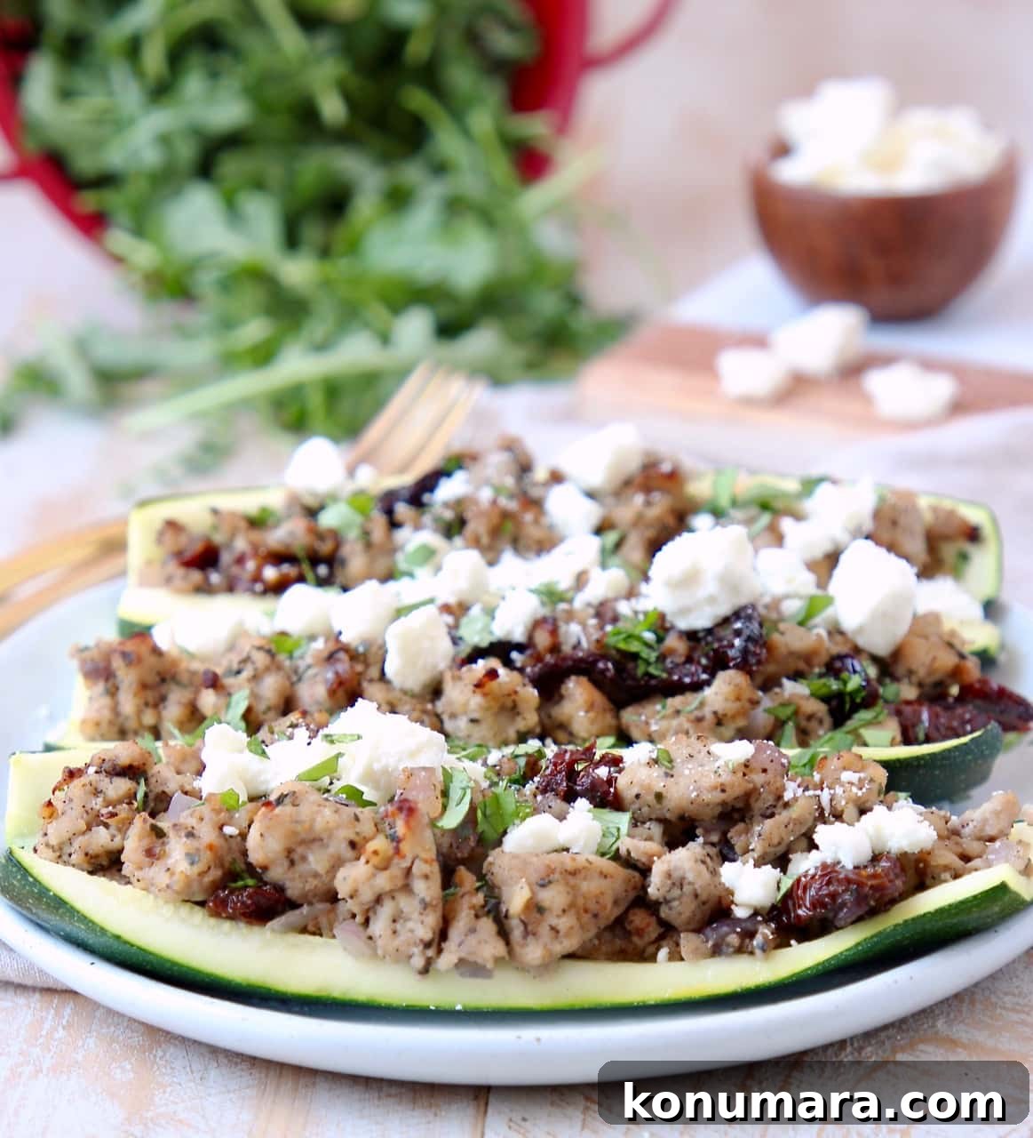 Greek Turkey-Stuffed Zucchini Boats with Feta 5 Ground Turkey, Sun Dried Tomato and Feta Cheese in hollowed zucchini halves on white plate