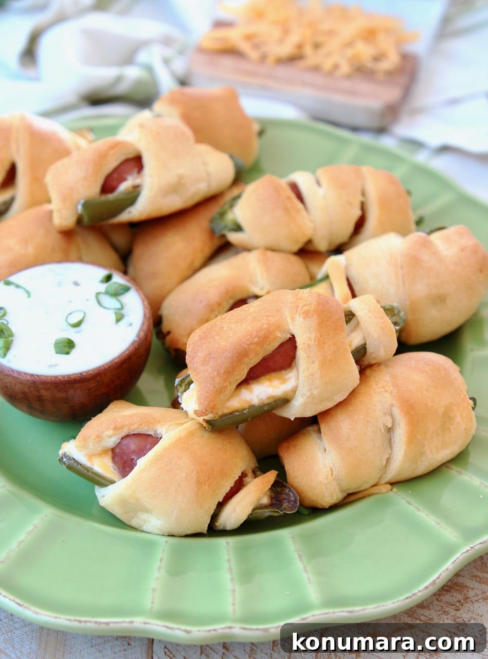 Jalapeno Poppers with a Little Smokie Sausage Wrapped in Crescent Rolls on a Green Plate with Cheddar Cheese and Ranch Dressing
