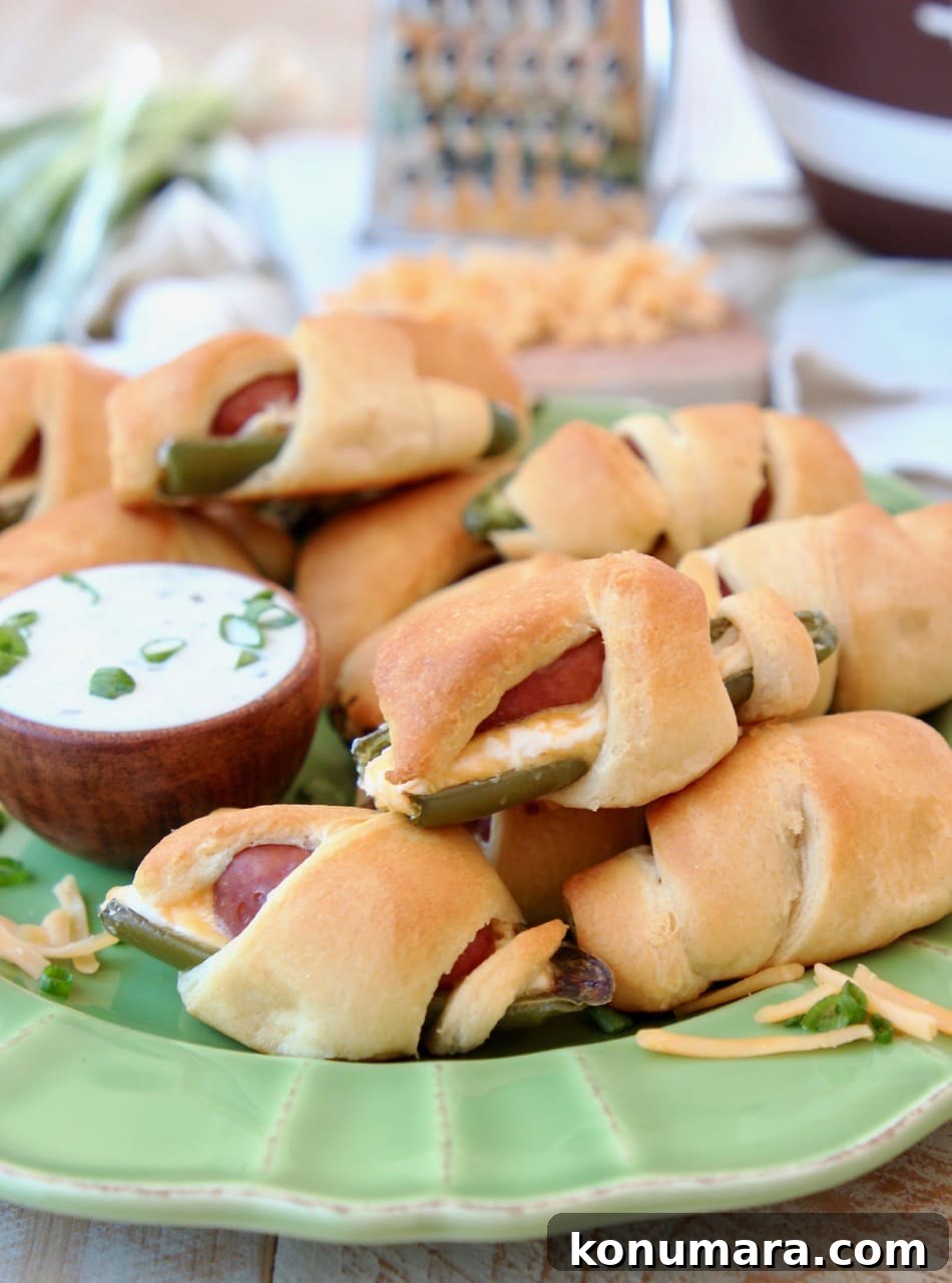Jalapeno Poppers with a Little Smokie Sausage Wrapped in Crescent Rolls on a Green Plate with Cheddar Cheese and Ranch Dressing