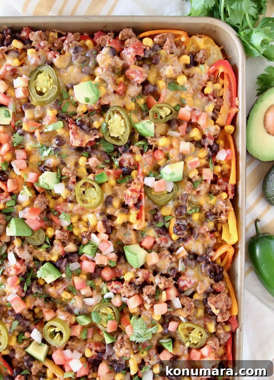 Low carb nachos on a baking sheet with avocado and jalapeno