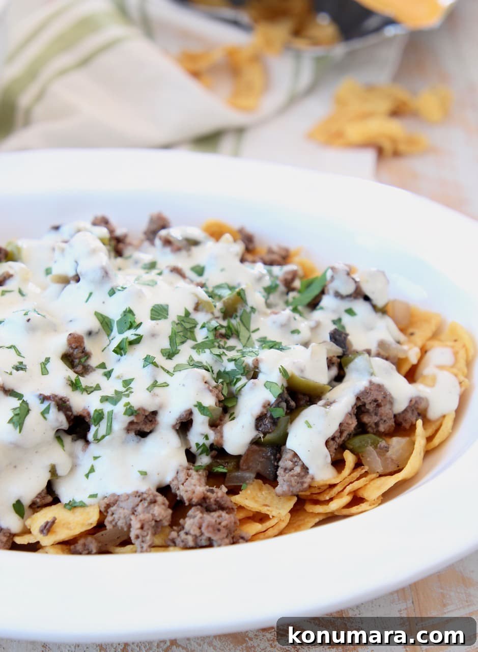 Fritos topped with ground beef and creamy provolone sauce in casserole dish
