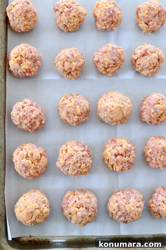 uncooked sausage balls on parchment-lined baking sheet