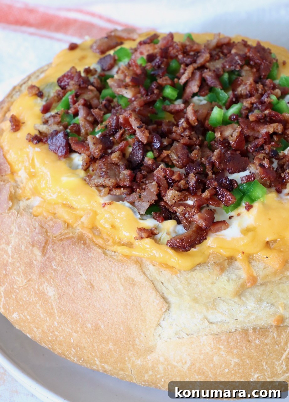 Cheesy Jalapeno Popper Bread Bowl Recipe 7 Round bread loaf hollowed and filled with melted cheese, topped with crispy bacon bits and chopped green peppers.