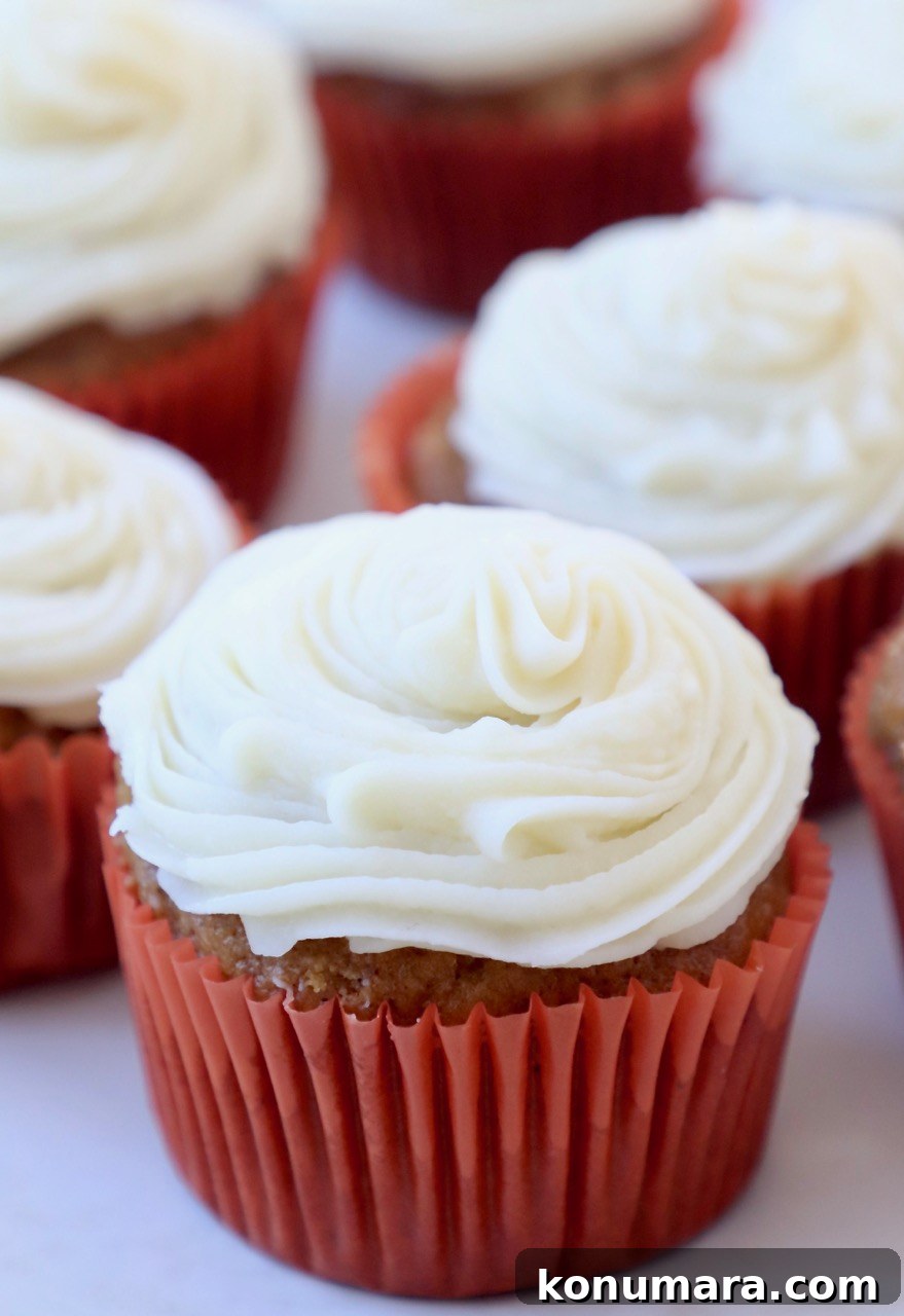 Moist Pumpkin Cupcakes with Tangy Cream Cheese Frosting 2 pumpkin cupcakes on plate topped with cream cheese frosting