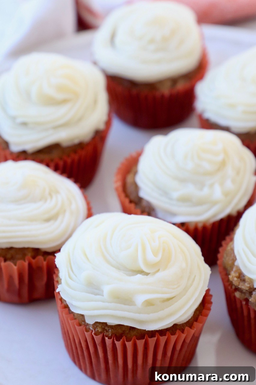 Moist Pumpkin Cupcakes with Tangy Cream Cheese Frosting 11 pumpkin cupcakes with cream cheese frosting in orange paper liners on plate