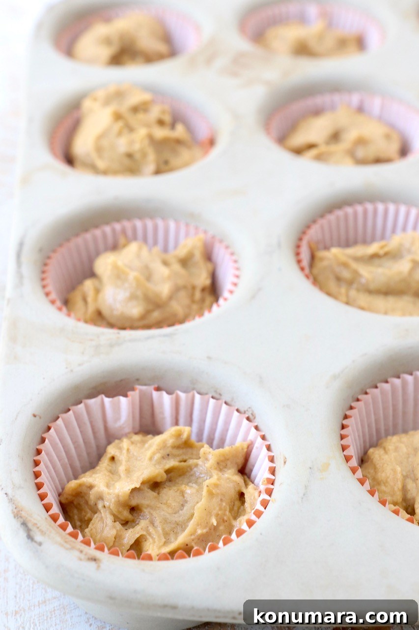 Moist Pumpkin Cupcakes with Tangy Cream Cheese Frosting 8 cupcake liners in muffin pan filled with pumpkin cupcake batter