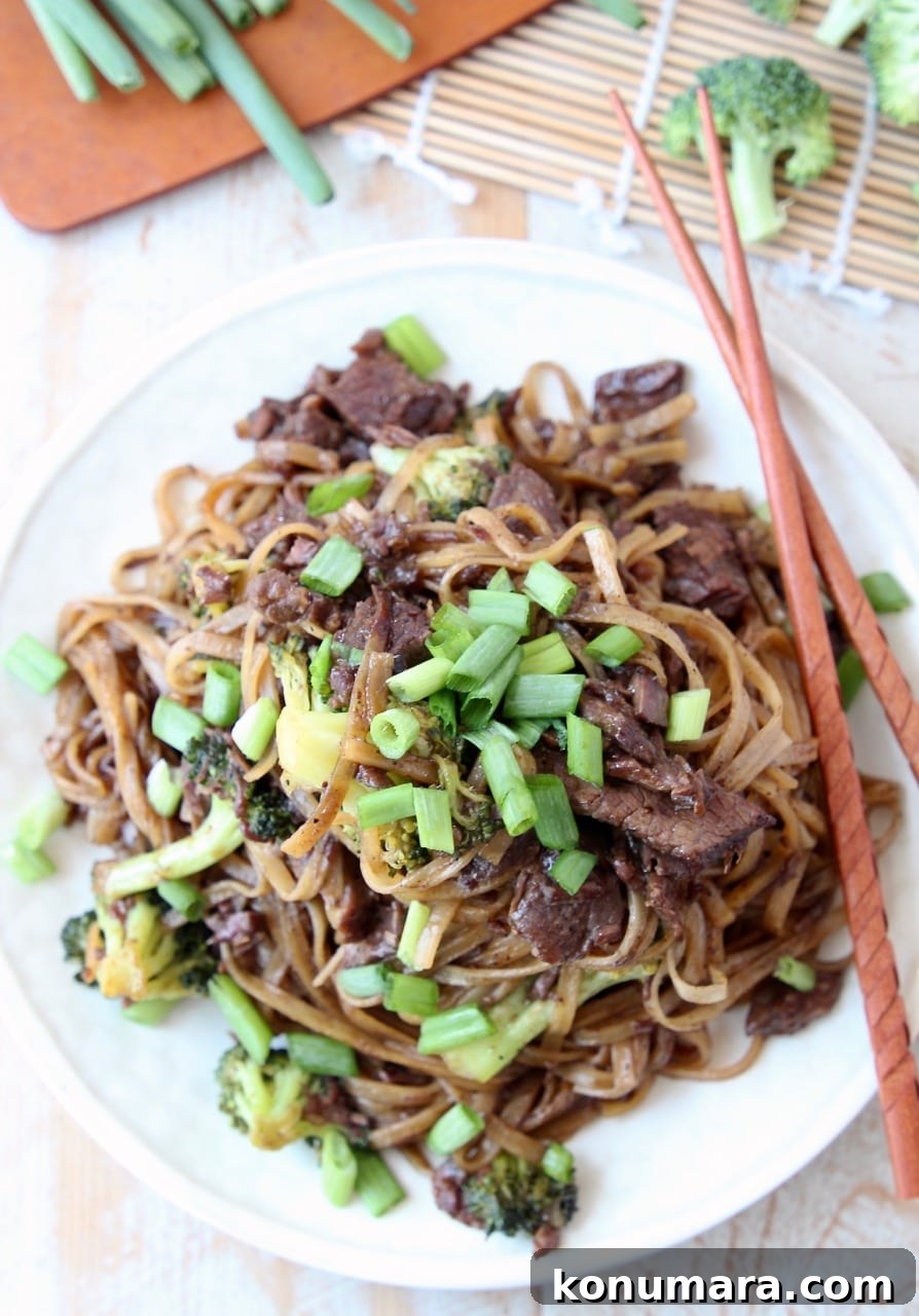 Slow Cooker Black Pepper Beef with Broccoli Recipe 4 Beef and broccoli with rice noodles and scallions on plate with chopsticks
